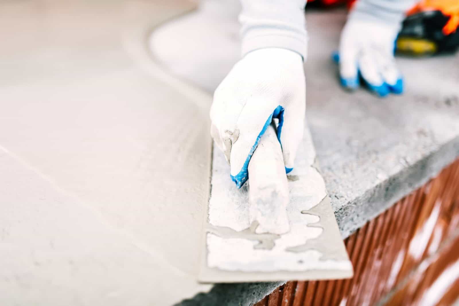 close-up of worker steel trowel and hand, using plastering tools