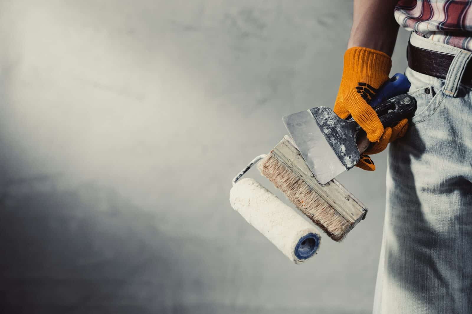 Construction worker man and concrete plaster wall. Hand and construction tools for house renovation