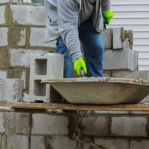 Bricklayers new house wall on foundation hands with in masonry bricklaying