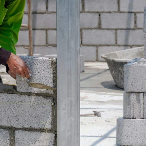 Cropped image of bricklayer making interior brick wall inside of house construction site