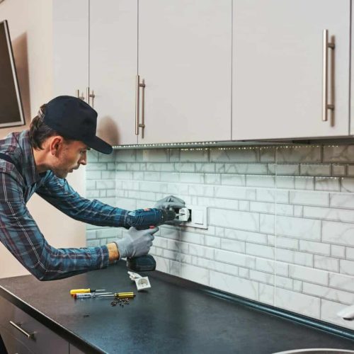 Electricity protection. Side view of young handyman with perforator