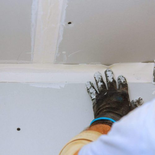 house improvements. putting plaster on the wall with spatula hand holding plastering tool