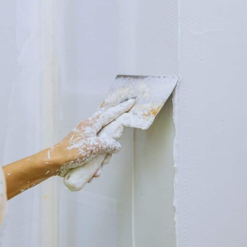 Male builder repairs wall with a spatula plaster on a wall