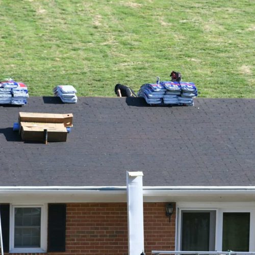 Roofers roofing company repairing a damaged roof with holes, insurance claim storm damage